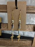 Pair of blue, white and gold beaded earrings on a brown earring card.