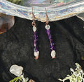 Pair of dangle earrings with purple amethyst and blue moonstone beads on a black background.